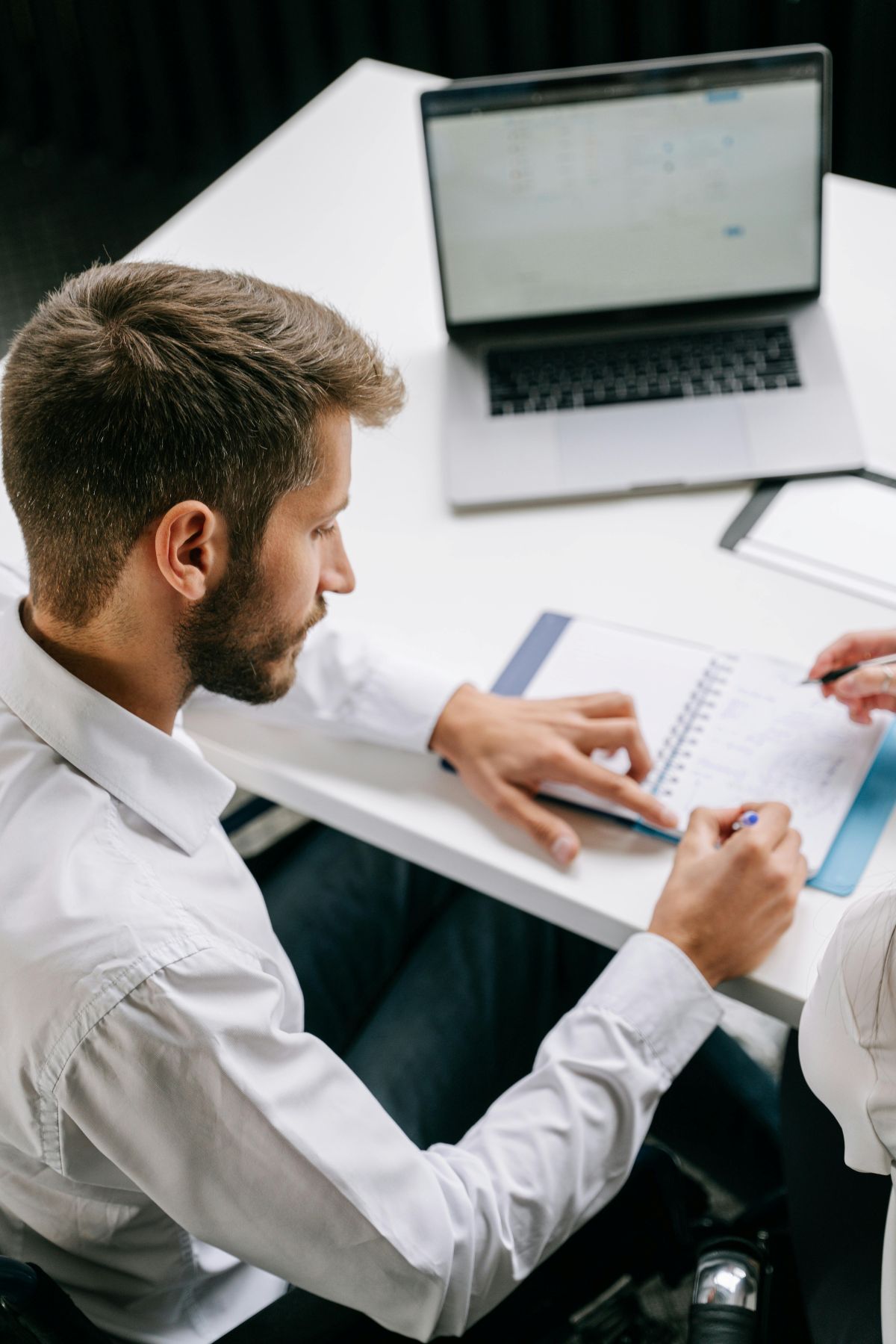 Conseiller en réunion prenant des notes et utilisant un ordinateur, illustrant l'accompagnement institutionnel des 2 Rives